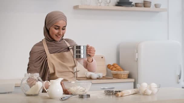 Feliz musulmán esposa tamizar harina hacer masa hornear en cocina — Vídeo de stock