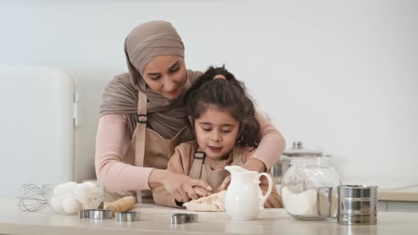 Мусульманская мама и дочь прикладывают деньги к выпечке на кухне — стоковое видео