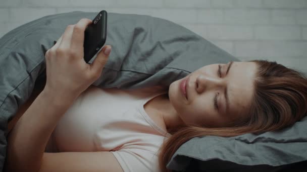 Depressive Frau liegt mit Smartphone zu Hause im Bett — Stockvideo