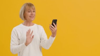 Uzak mesafeden ailenle konuş. Akrabalara seslenen, akıllı telefonlara el sallayan ve gülümseyen son sınıf öğrencisi kadın videosu.