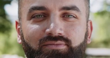 Neşeli bir ruh hali. Kameraya göz kırpan ve gülümseyen neşeli, olgun, sakallı, yeşil gözlü bir adamın portresini yakından çek.