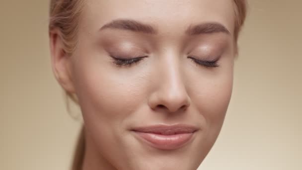 Natural beauty. Attractive young blonde lady smiling to camera over beige studio background, slow motion — Stock Video