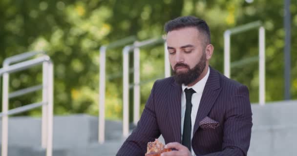 Close-up portret van gelukkig corporate werknemer met pizza voor de lunch, zitten op de trap in het stadspark, slow motion — Stockvideo