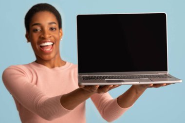 Elinde siyah ekranı olan neşeli Afrikalı Amerikalı kadın dizüstü bilgisayar tutuyor.