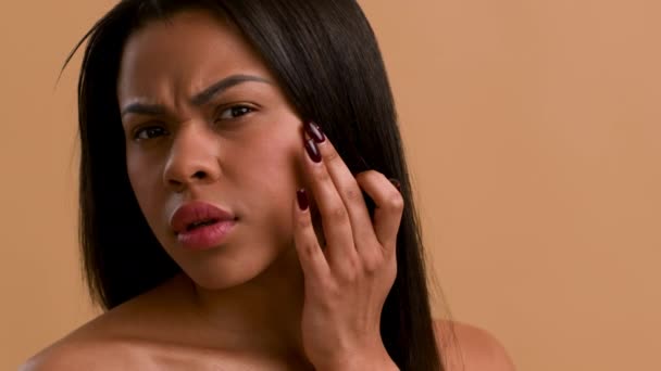 베이지 배경 위 의 치크 에 손을 대고 있는 분열된 흑인 여인 — 비디오