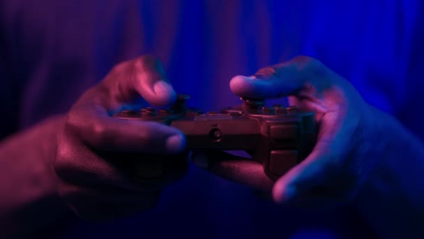 Cyber sport e gioco online. Primo piano del joystick in mani maschili nere, ragazzo che gioca ai videogiochi con luci al neon — Video Stock