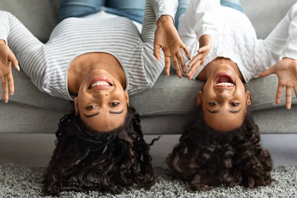 Смешные мать и дочь лежали на диване вверх ногами — стоковое фото