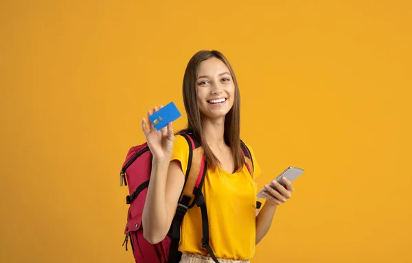 Szczęśliwa kobieta Backpacker ze smartfonem i kartą kredytową na żółty — Zdjęcie stockowe