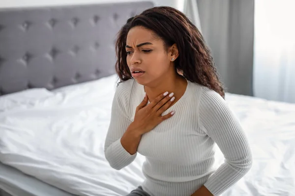 Молода чорна жінка кашляє, страждає від болю в горлі — стокове фото