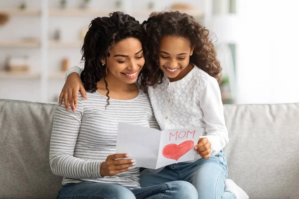 Glad svart tjej med presentkort kramar sin mamma — Stockfoto