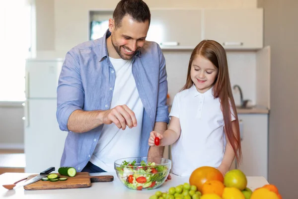 キッチンでサラダを準備パパと幸せな女の子の料理 — ストック写真