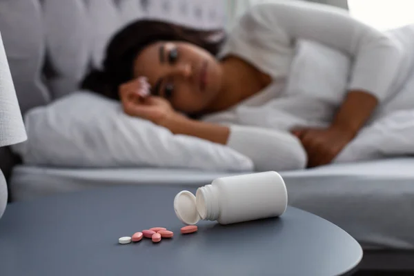 Zwarte vrouw lijdt aan slapeloosheid, pillen op tafel — Stockfoto