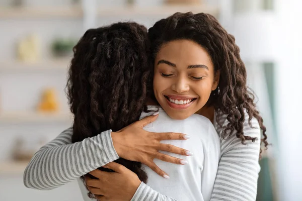 Szerető fekete anya átöleli lányát, otthon belső — Stock Fotó