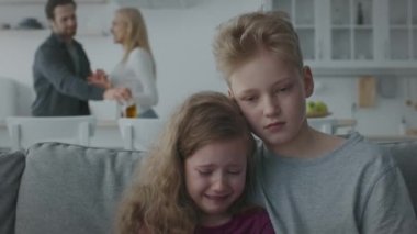 Küçük çocuk ve kız kanepede kaynaşıyor, gürültülü ebeveyn tartışması, kızgın anne ve sarhoş baba kavga ediyor.