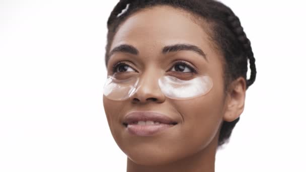 Beauty portrait of young african american lady with cooling hydrogel patches under eyes area, white studio background — Stock Video