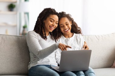Heyecanlı Afrikalı Amerikalı anne ve çocuk birlikte dizüstü bilgisayar kullanıyor.