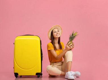 Yazlık giysiler içinde pembe ananas tutan bir kadın.