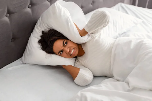 Stres czarny kobieta przykrywa uszy leżące w łóżku — Zdjęcie stockowe