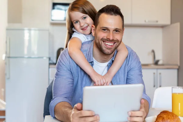 Pai alegre e pequena filha usando computador tablet na cozinha — Fotografia de Stock