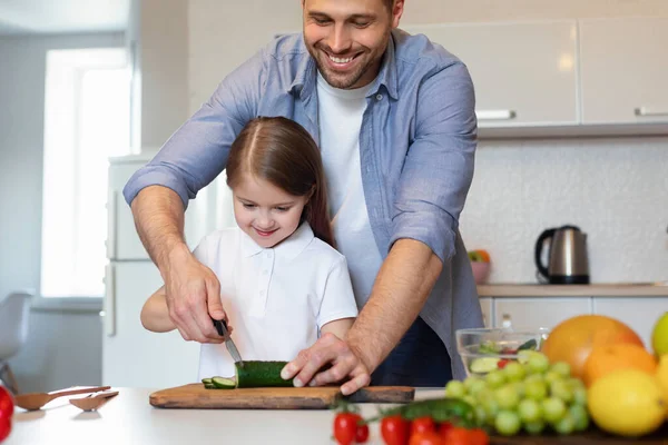 Padre e hija cocinando ensalada cortando verduras juntos en la cocina — Foto de Stock