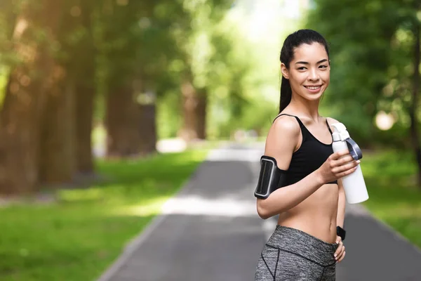 Atletisch jong aziatisch meisje nemen pauze in training buiten, drinken van water — Stockfoto