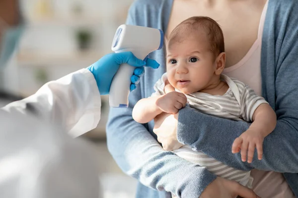 Невідомий лікар Перевірка температури тіла новонароджених з інфрачервоним термометром — стокове фото