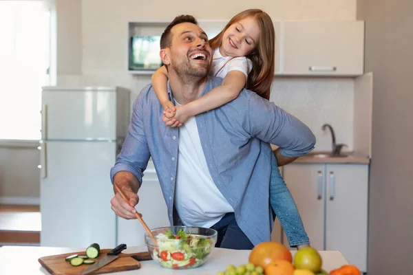 幼い娘は台所で料理をしている間にパパを抱きしめる — ストック写真