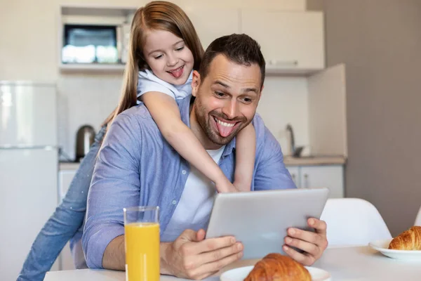 Filha abraçando papai fazendo selfie em tablet se divertindo dentro de casa — Fotografia de Stock