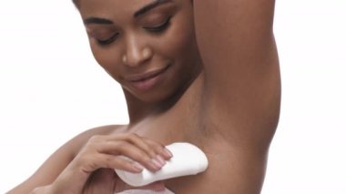 Kişisel hijyen. Güzel, Afro-Amerikan bayan, beyaz stüdyo arka planına deodorant sürüyor.