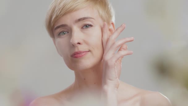 Concepto de feminidad. Retrato de belleza de mujer atractiva de mediana edad tocando su piel lisa, mirando a la cámara — Vídeo de stock