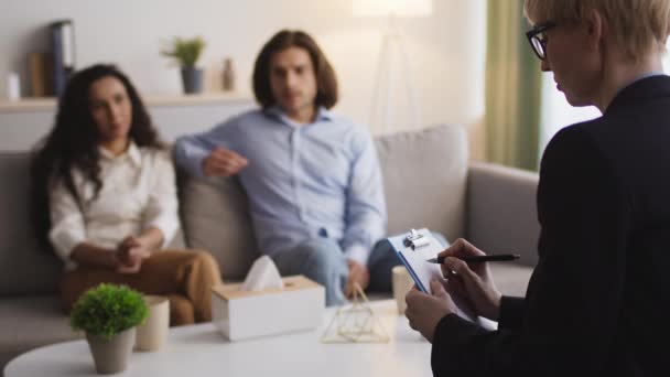 Psicoterapeuta feminina tomar notas, escrever diagnóstico de cônjuges jovens com problemas de relacionamento durante a consulta — Vídeo de Stock