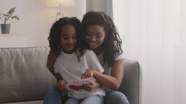 Glad mödradag. Ung glad afrikansk amerikansk kvinna läser handgjorda gratulationskort och kramar sin dotter — Stockvideo