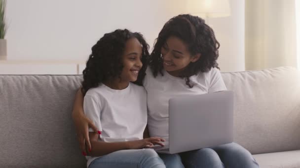 Joven madre afroamericana ayudando a su hija a usar la computadora portátil, explicando las reglas de uso de Internet en casa, cámara lenta — Vídeos de Stock