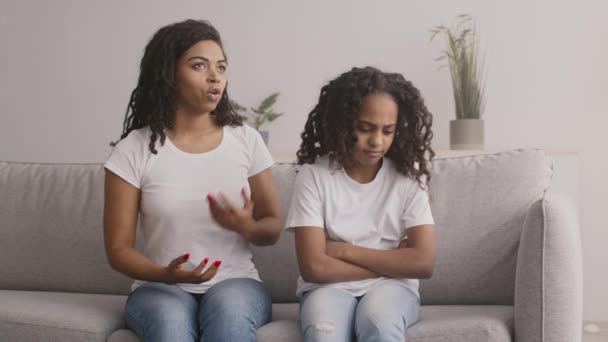 La reconciliación familiar. Mujer afroamericana joven sintiéndose pacífica y abrazando a su hija adolescente ofendida — Vídeos de Stock