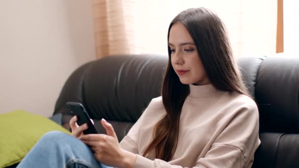 Junge selbstisolierte Frau vernetzt sich am Smartphone, scrollt Social-Media-Nachrichten auf dem Handy, sitzt zu Hause — Stockvideo