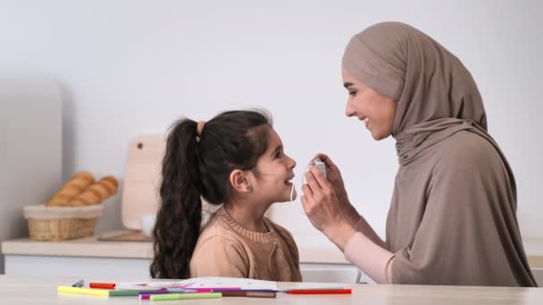 Muselman Mother Putting On Face Mask På Dotter Hemma — Stockvideo