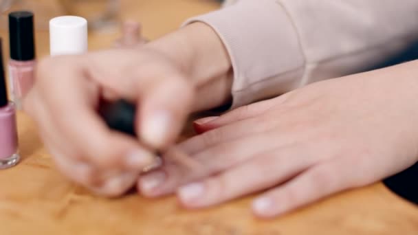 Οικιακό μανικιούρ. Κοντινό πλάνο της γυναίκας που εφαρμόζει μπεζ βερνίκι νυχιών στα νύχια της, κάθεται στο σπίτι, αργή κίνηση — Αρχείο Βίντεο