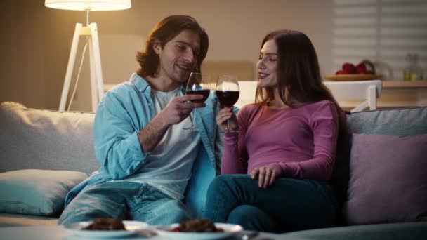 Jong koppel in liefde drinken wijn samen, man toasten met vriendin, het doorbrengen van romantische avond samen thuis — Stockvideo