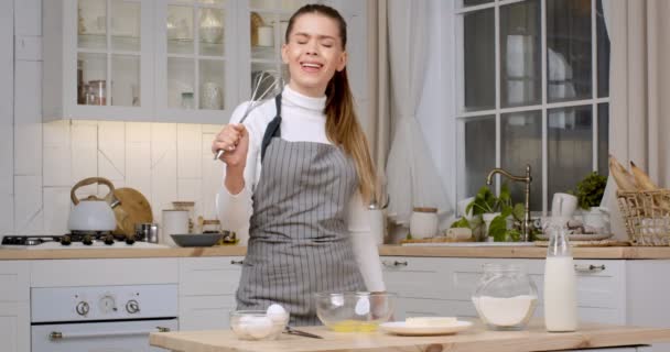 Trevlig mat. Ung dam kock sjunger i visp, låtsas vara sångare, förbereda deg för bakverk hemma kök — Stockvideo