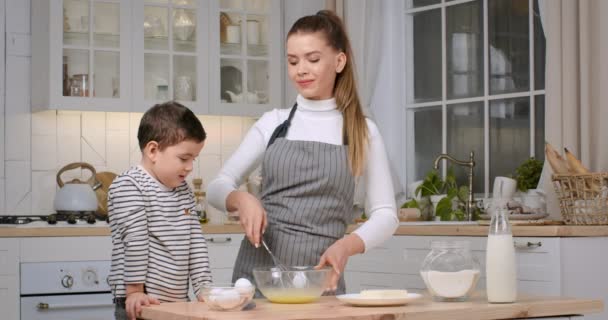 Jeune femme préparant la pâte avec son petit fils, se donnant cinq haut et riant à la caméra à la cuisine — Video