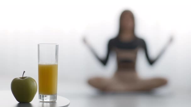 Kobieta uprawia jogę w domu, skupia się na jabłku i soku — Wideo stockowe