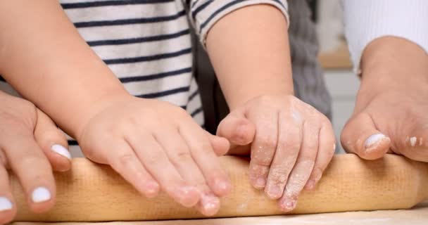 Kis cukrász. Közelkép kisfiús kezekről, akik tűvel szórják a tésztát, segítve anyát a konyhában sütni. — Stock videók