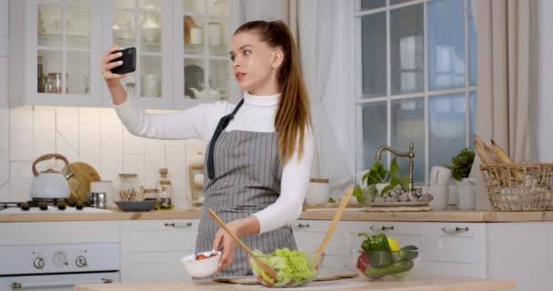 Кулинарный блог. Девушка-блогер записывает видео для социальных сетей, разговаривает с камерой смартфона, объясняя рецепт — стоковое видео