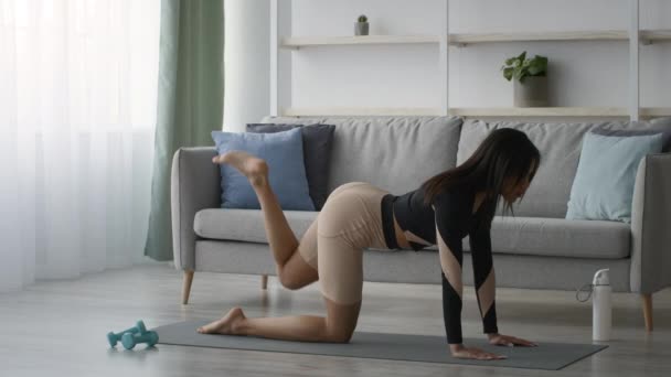 Dame noire faisant l'entraînement quadrupède d'exercice d'augmentation de jambe à la maison — Video
