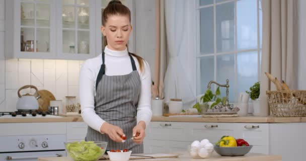 Joven ama de casa cocinando en la cocina, cortando tomates orgánicos frescos para ensalada de verduras, preparando la cena en casa — Vídeos de Stock