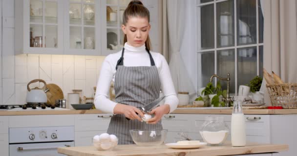Huiselijk bakken. Jonge vrouw banketbakker bereidt gebak thuis, slaat eieren voor deeg, staat in de keuken — Stockvideo