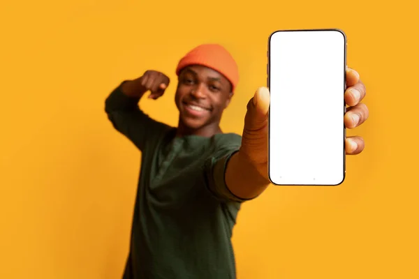 Wesoły czarny facet wskazując na smartfona z białym ekranem w rękach — Zdjęcie stockowe