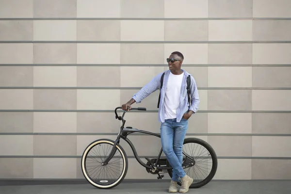 Estilo de vida urbano. Retrato de comprimento total do cara preto legal com bicicleta perto da parede de tijolo fora, espaço em branco — Fotografia de Stock