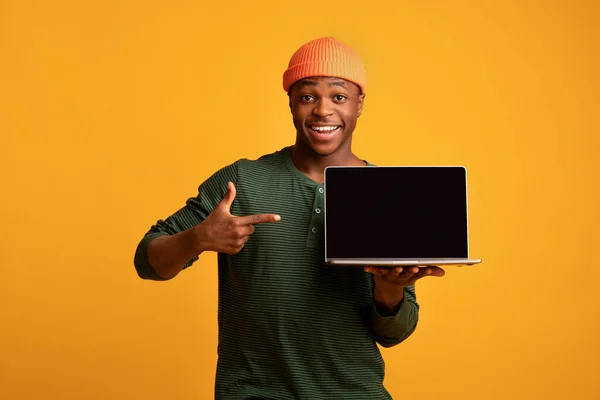 Site fixe. alegre Africano cara apontando para laptop computador com tela preta — Fotografia de Stock