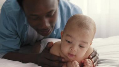 Sevimli bir bebek göbeğinde yatıyor, Afro-Amerikan babasını seviyor güzel bebeğine sarılıyor ve onu öpüyor.
